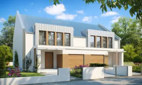 Wizualizacja komputerowa przedstawia nowoczesny, piętrowy dom bliźniaczy o minimalistycznej architekturze. Elewacja budynku łączy jasny, biały tynk z elementami w kolorze ciepłego drewna, które otaczają okna oraz pokrywają bramy garażowe umieszczone w centralnej części parteru. Budynek zwieńczony jest dwuspadowym dachem o jasnoszarej, blaszanej nawierzchni, urozmaiconym nowoczesnymi lukarnami (lukarnami pulpitowymi) z pionowym deskowaniem. Na piętrze każdego z segmentów znajdują się duże przeszklenia zabezpieczone prostymi, metalowymi balustradami. Przed domem widoczna jest zaaranżowana strefa wejściowa z drewnianymi drzwiami, niewielki ogródek z kwitnącymi, różowymi krzewami oraz niskie, białe ogrodzenie z otwartą bramą wjazdową. Całość otacza bujna, zielona roślinność i drzewa pod jasnoniebieskim niebem z nielicznymi, białymi chmurami.